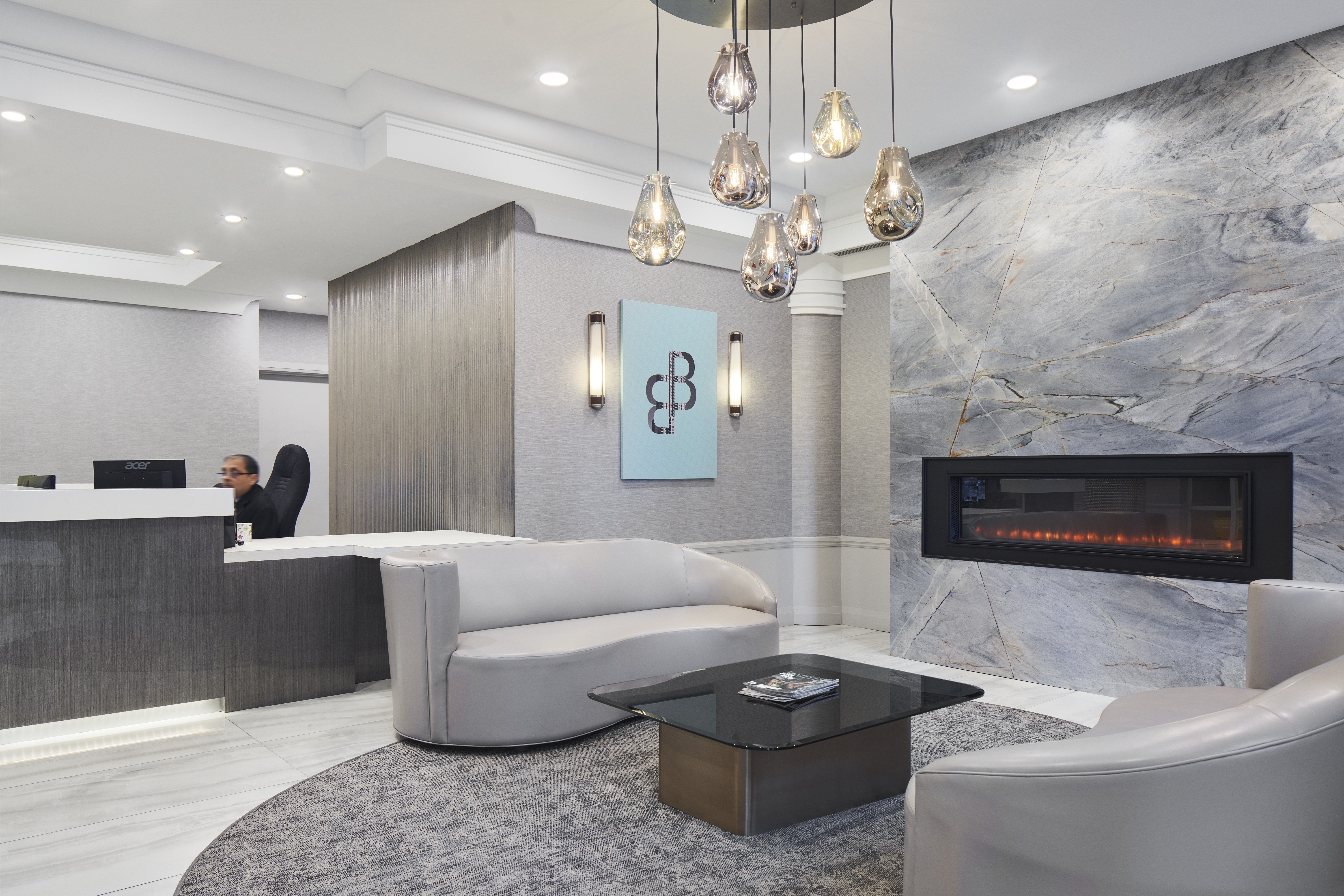 A modern office lobby with a reception desk and a fireplace.